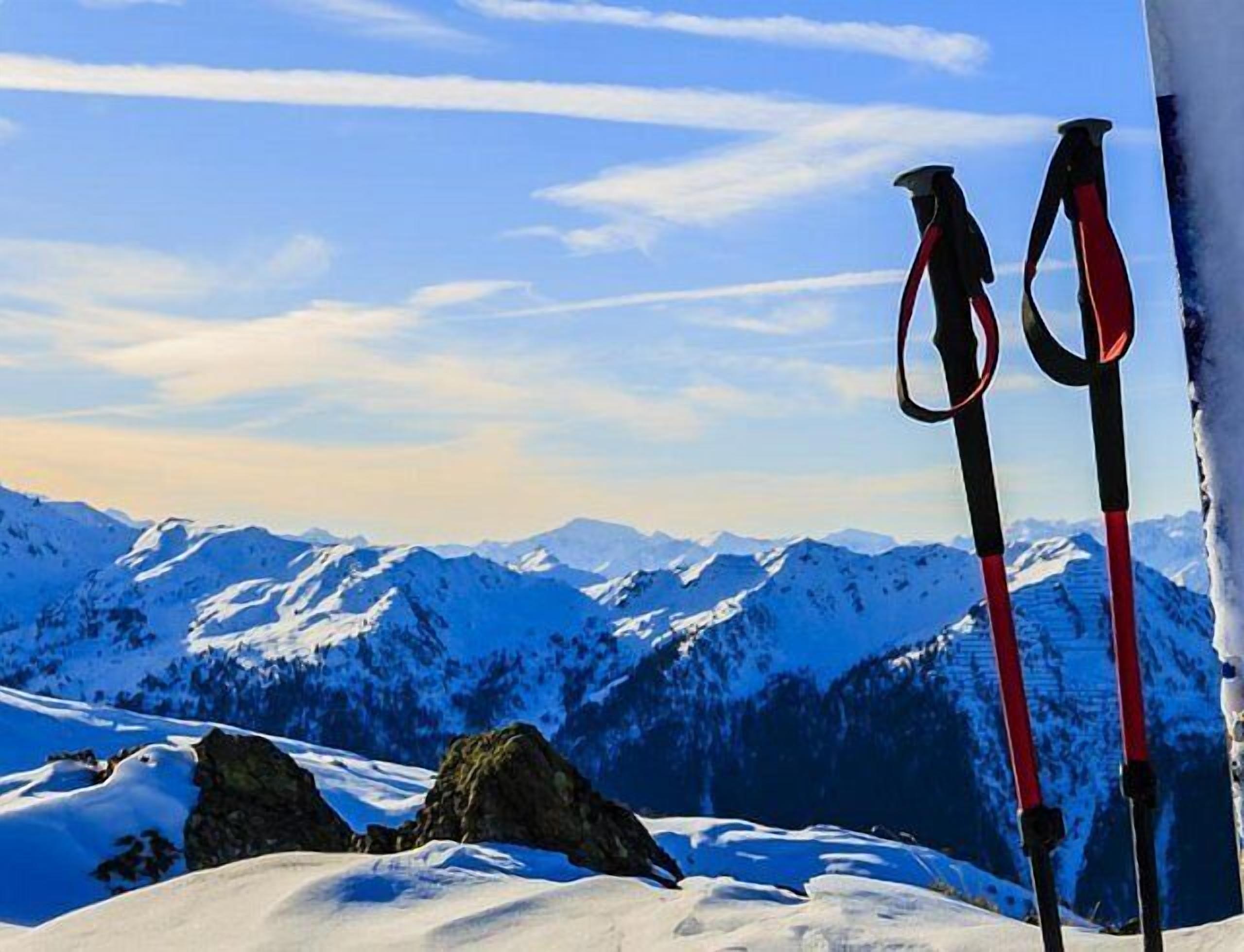 Eine verschneite Berglandschaft mit zwei Ski und zwei Skistöcken, die an einem mit Schnee bedeckten Felsen angelehnt sind.