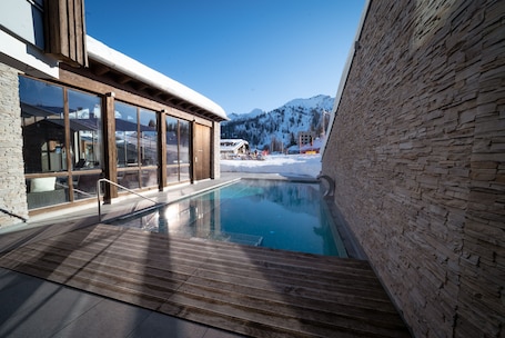 Una piscina techada, una piscina al aire libre, sombrillas