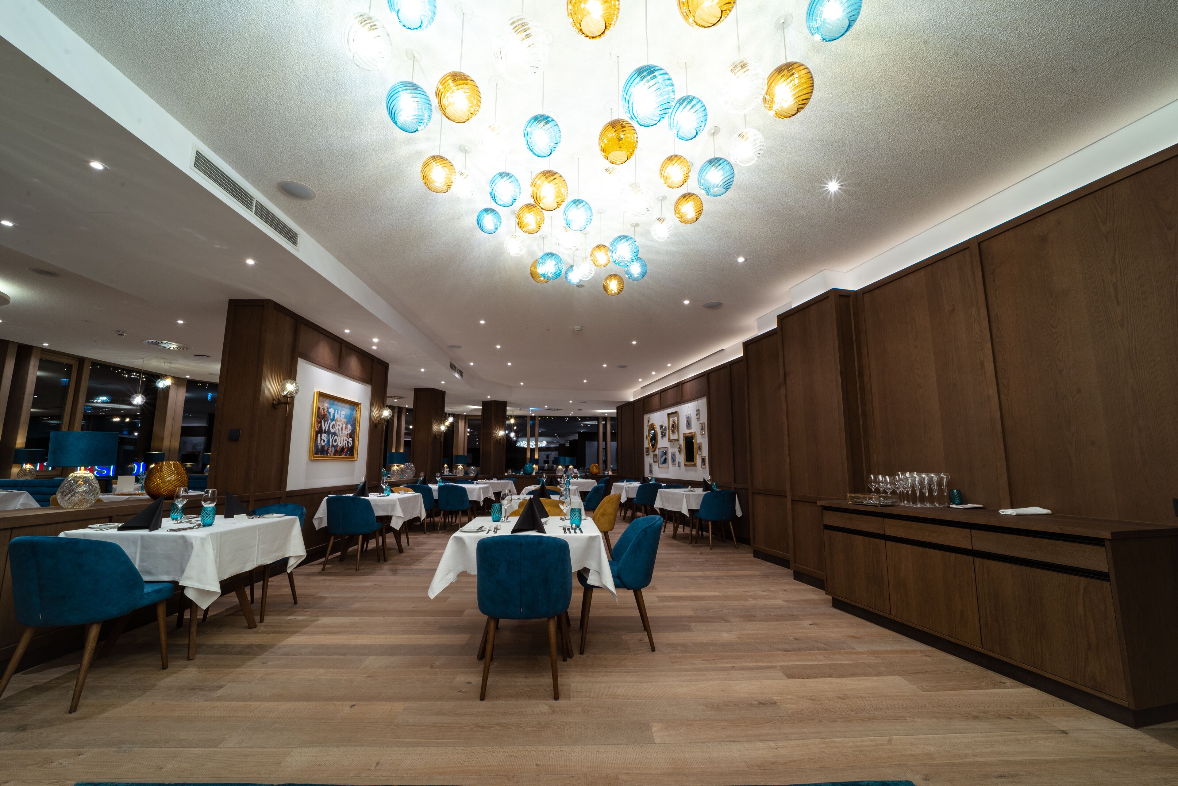 Un restaurante con varias mesas, sillas azules y una barra de madera.