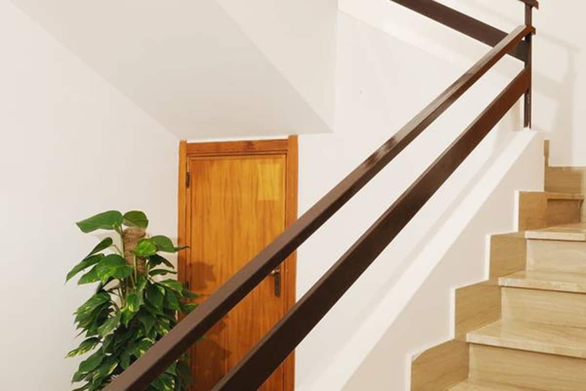 A staircase with wooden steps and a dark metal handrail, leading to a wooden door.