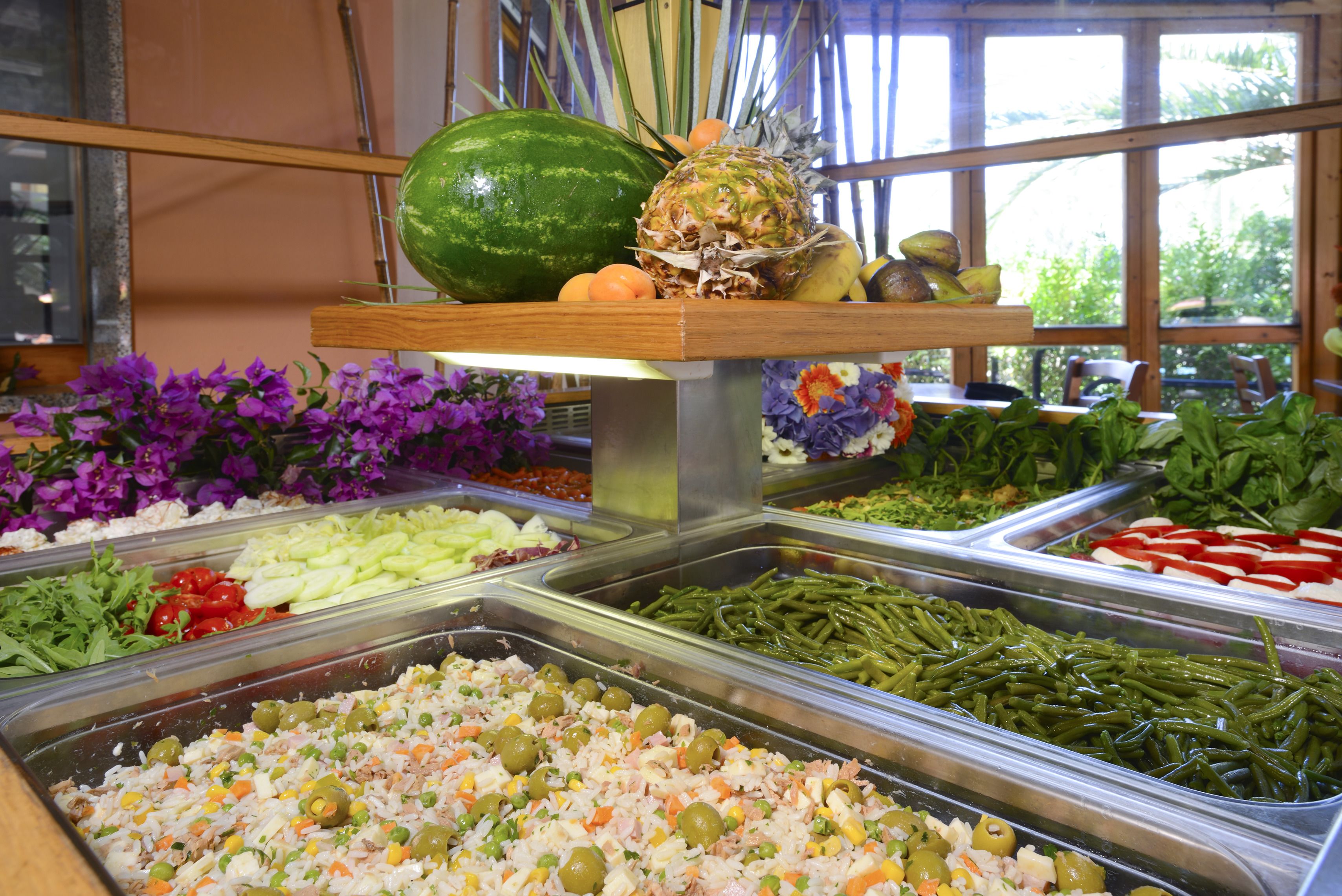 Un bufé con diversas opciones de comida, incluyendo ensaladas, frutas y platos cocinados.