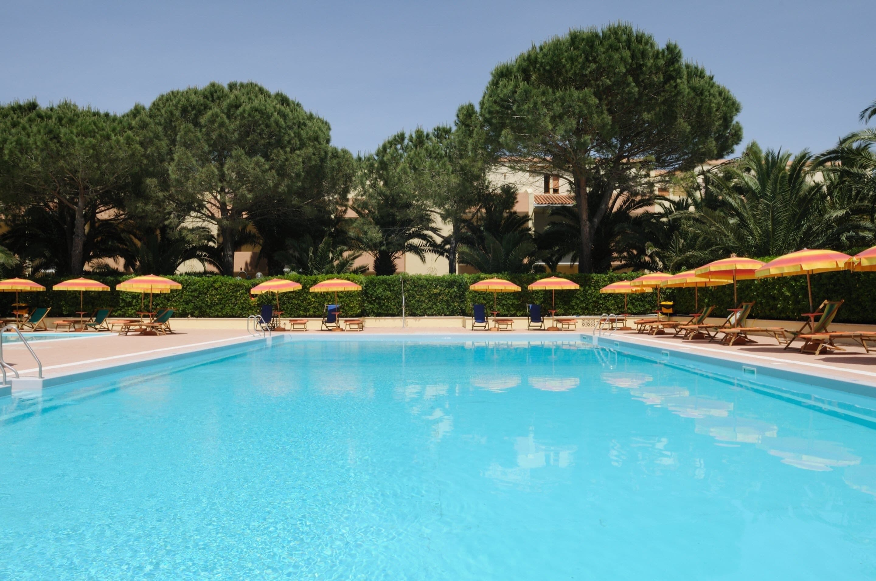 A swimming pool with sun umbrellas and lounge chairs.