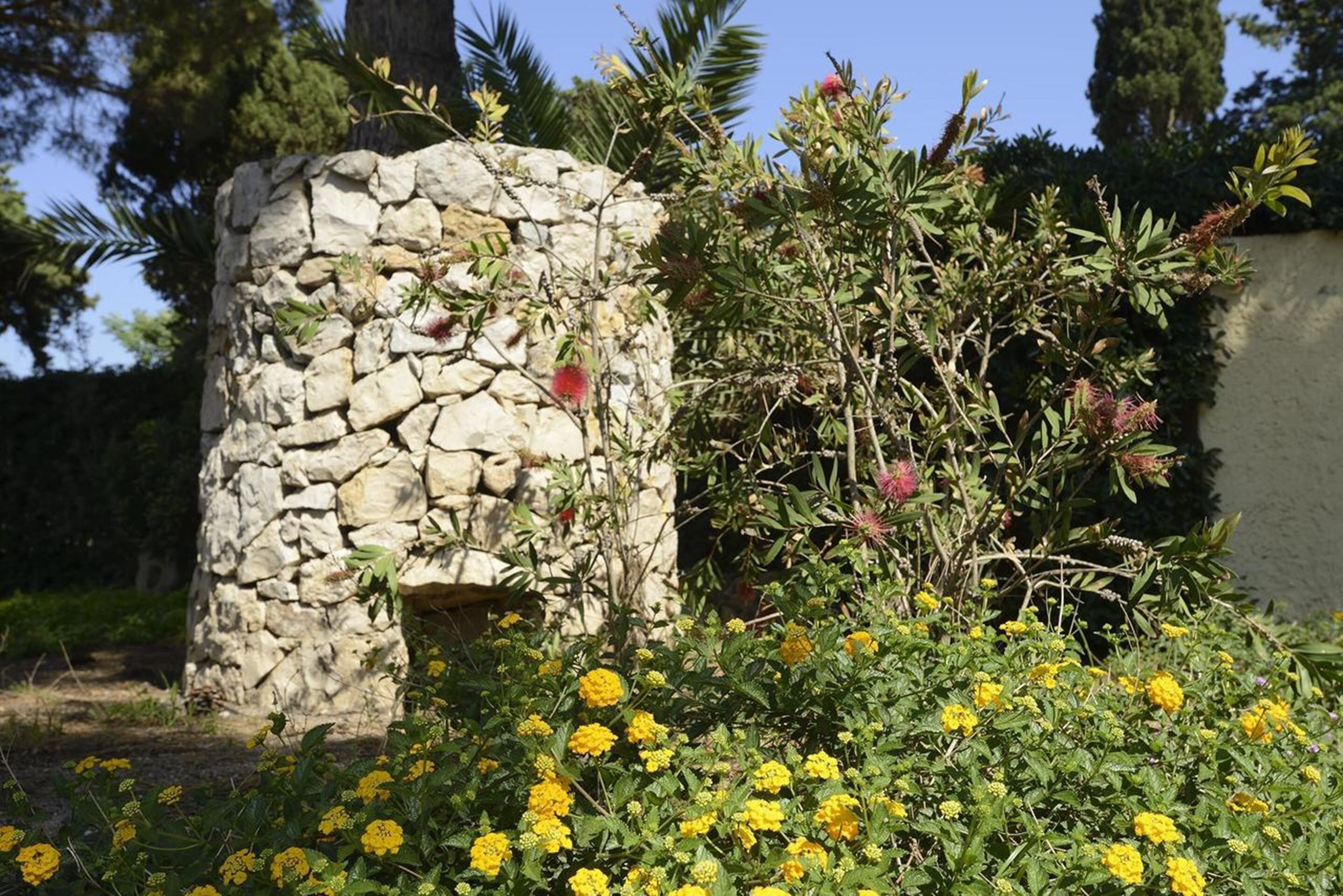Une construction en pierre, avec des fleurs jaunes devant.