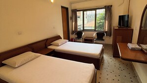 A hotel room with two beds, a desk with a TV, a ceiling fan, and a window with curtains. - Hotel J.B. (Johor Bahru)