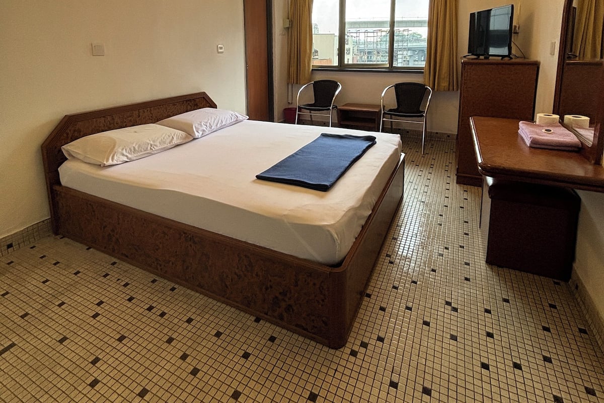 A hotel room with a bed, a desk, a chair, a television, and a window with a view.