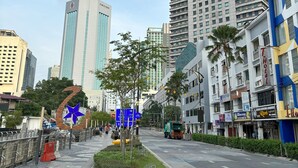 A city street with tall buildings, a blue star decoration, and a road with a green bus. - Hotel J.B. (Johor Bahru)