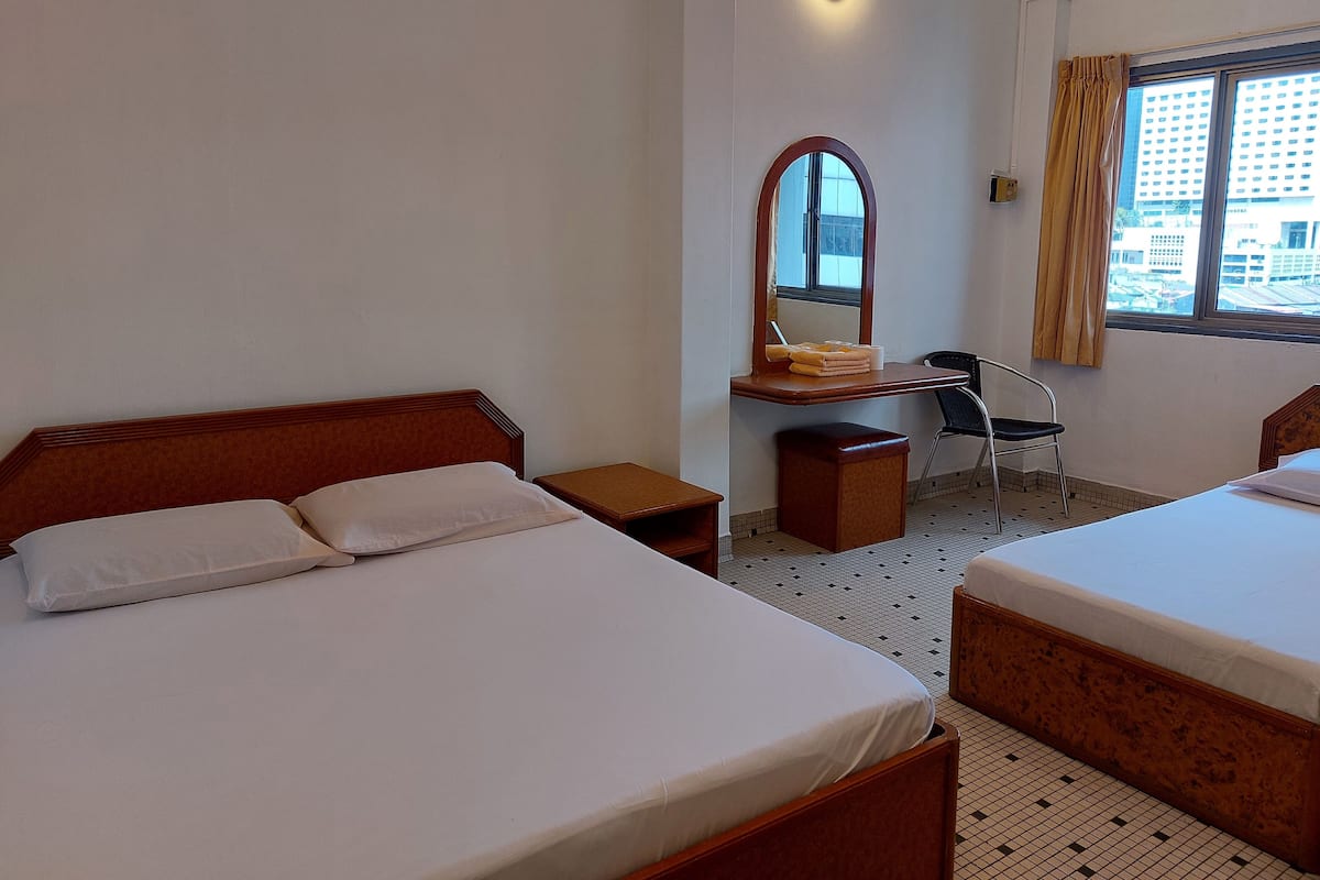 A hotel room with two beds, a desk with a mirror, a chair, and a window with curtains.
