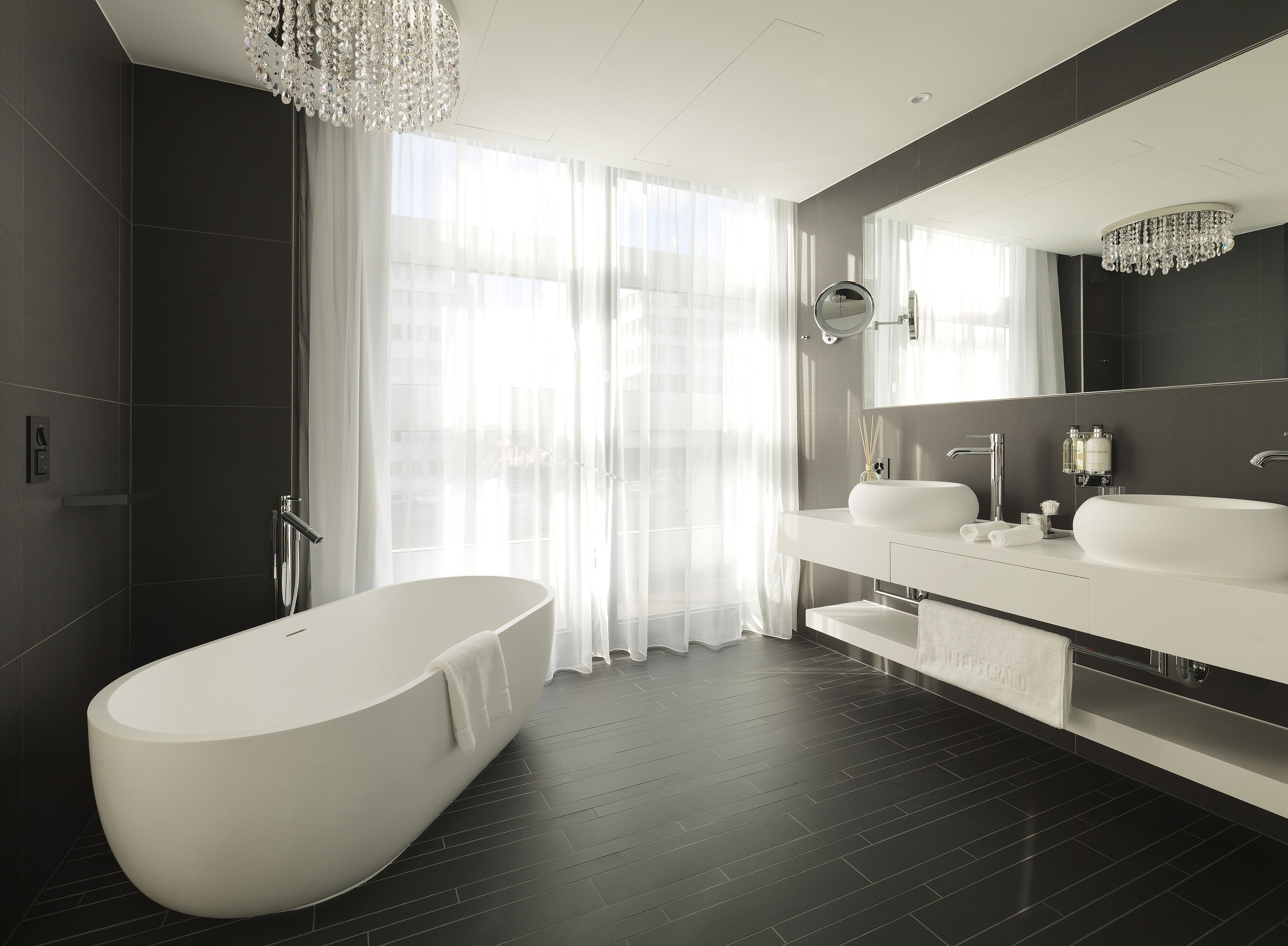 Une salle de bain moderne avec une baignoire sur pieds, un grand miroir et un meuble-lavabo doté d’un évier et d’un porte-serviettes.