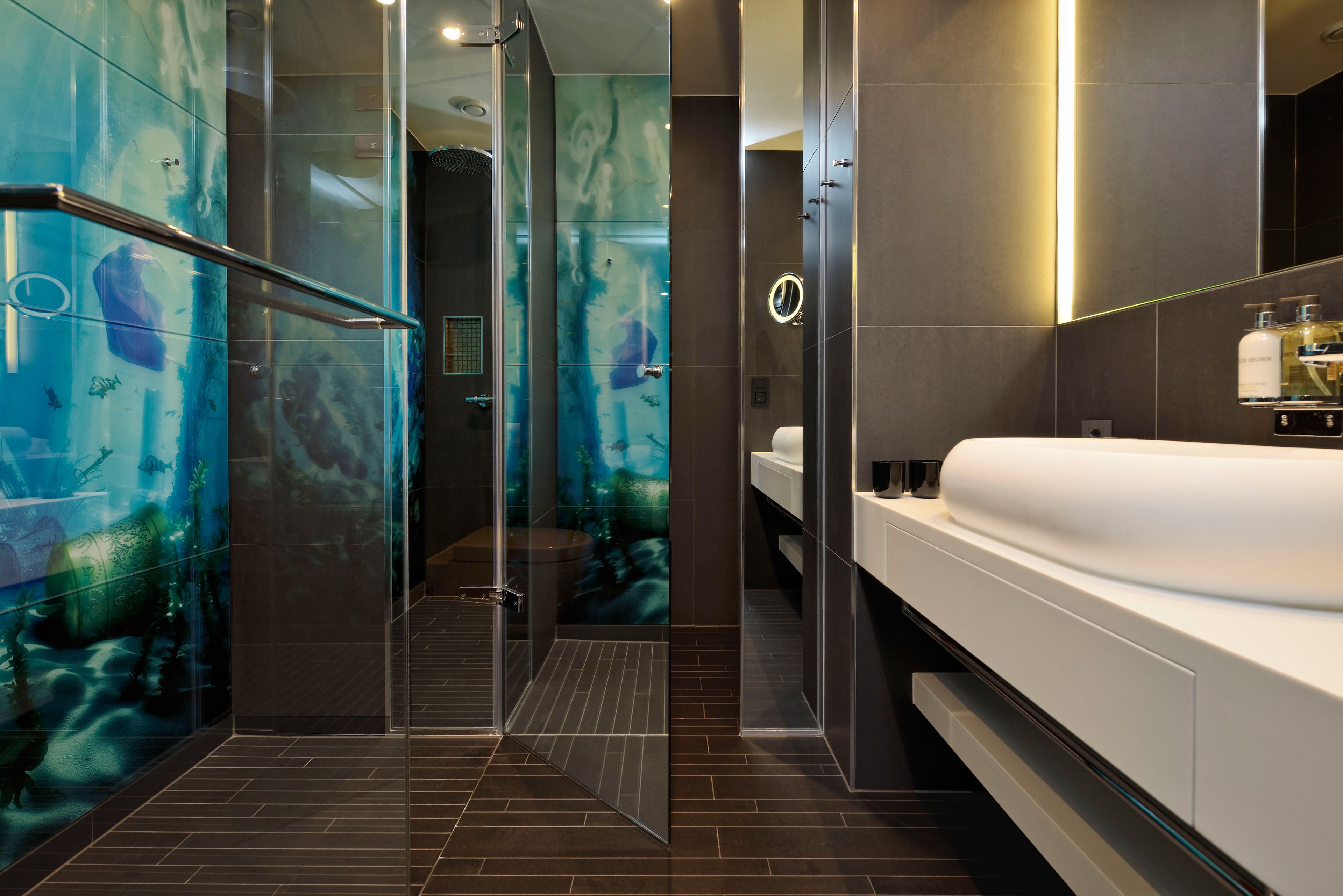 Un baño moderno con cabina de ducha de vidrio, un lavamanos blanco y un espejo grande.