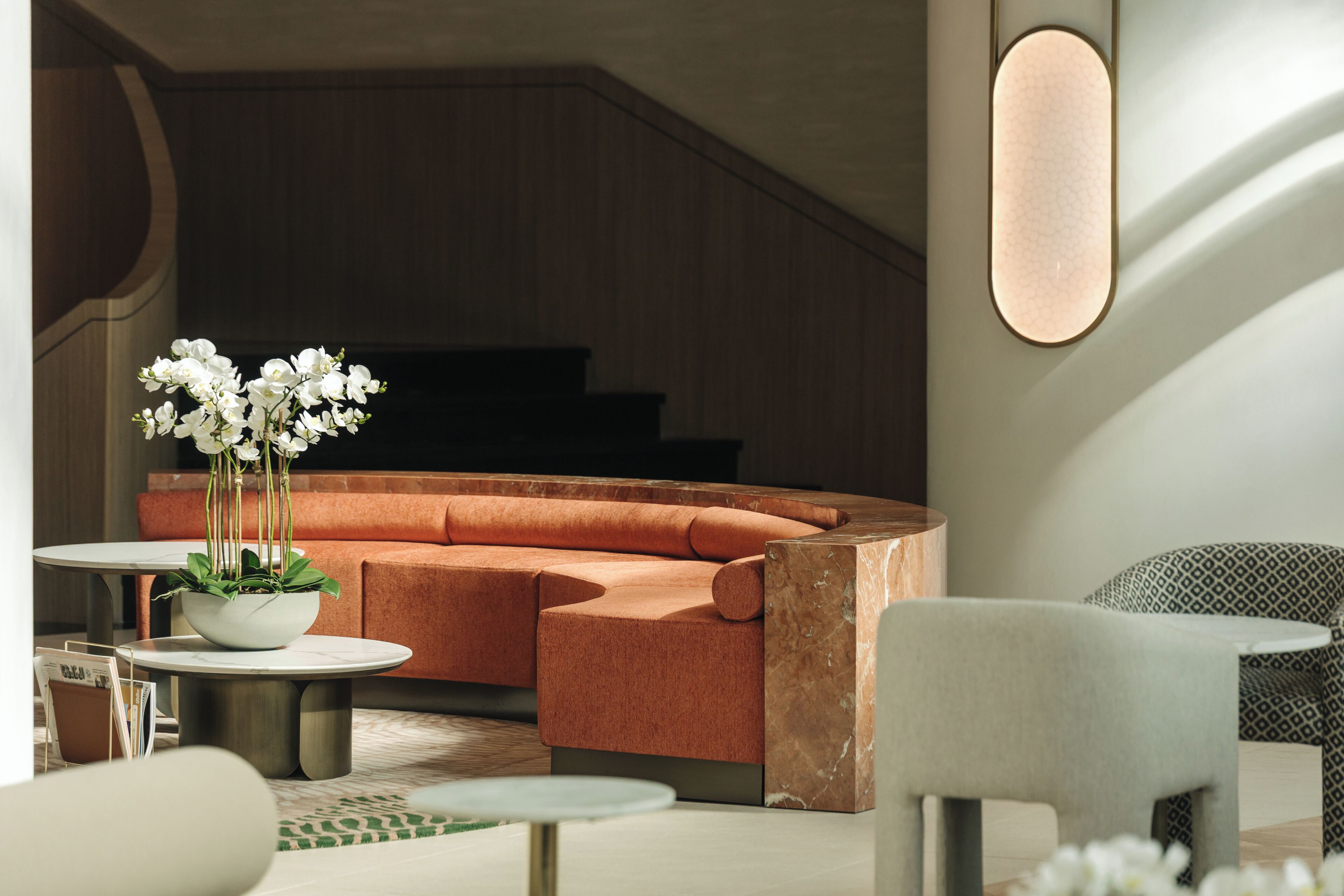 A modern interior with a curved sofa, a round table, and a potted plant.