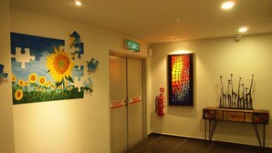 A hallway with a puzzle piece wall art, a fire extinguisher, and a door labeled "KELUAR". - M2 Hotel Melaka (Malacca City)