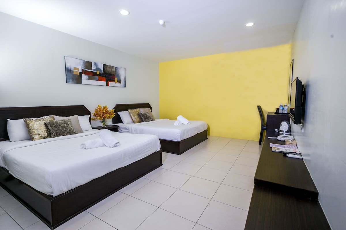 Habitación de hotel con dos camas, un escritorio, una silla y un televisor.