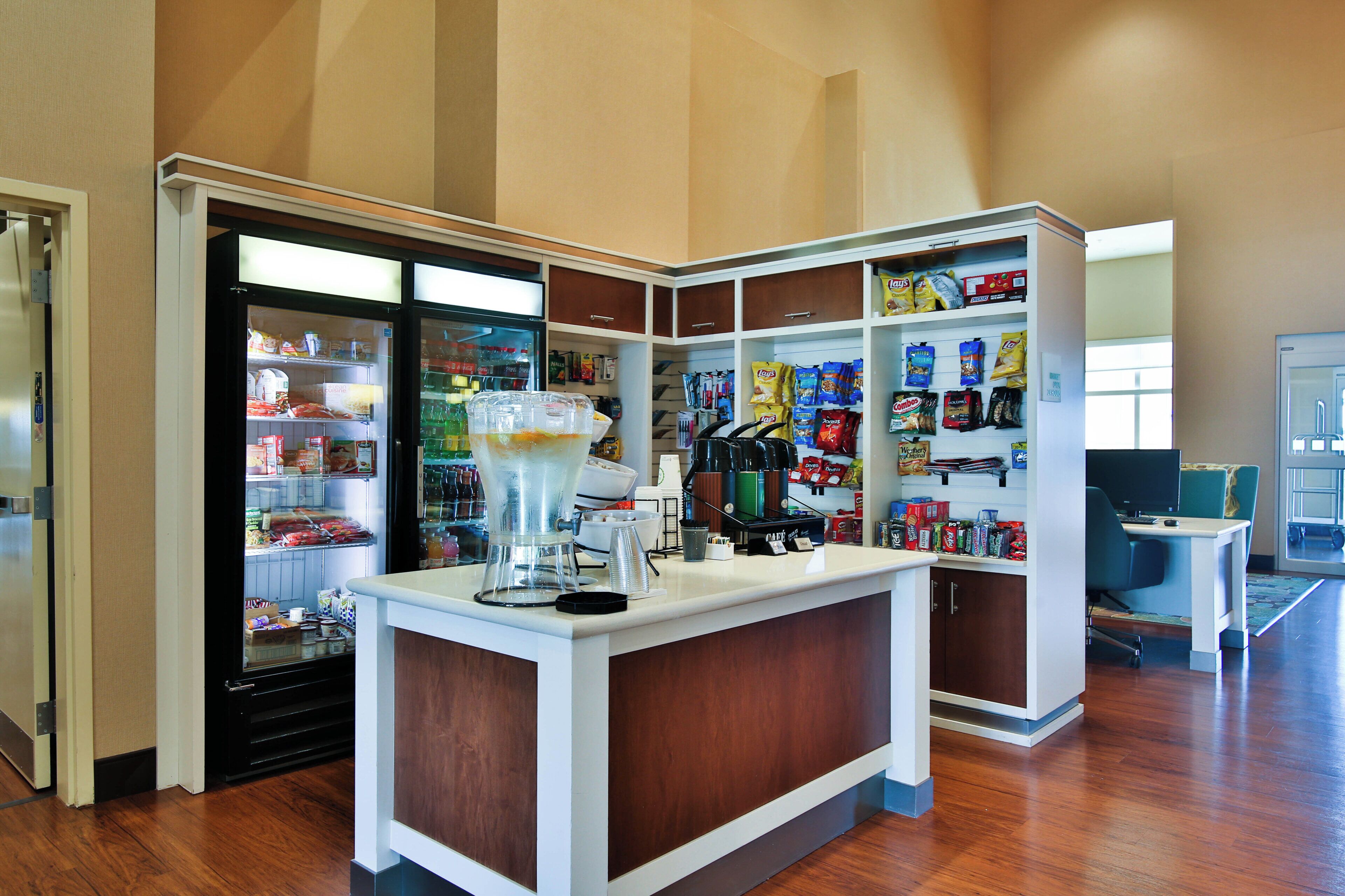 A self-service area with a beverage dispenser, snack shelves, and a coffee machine.