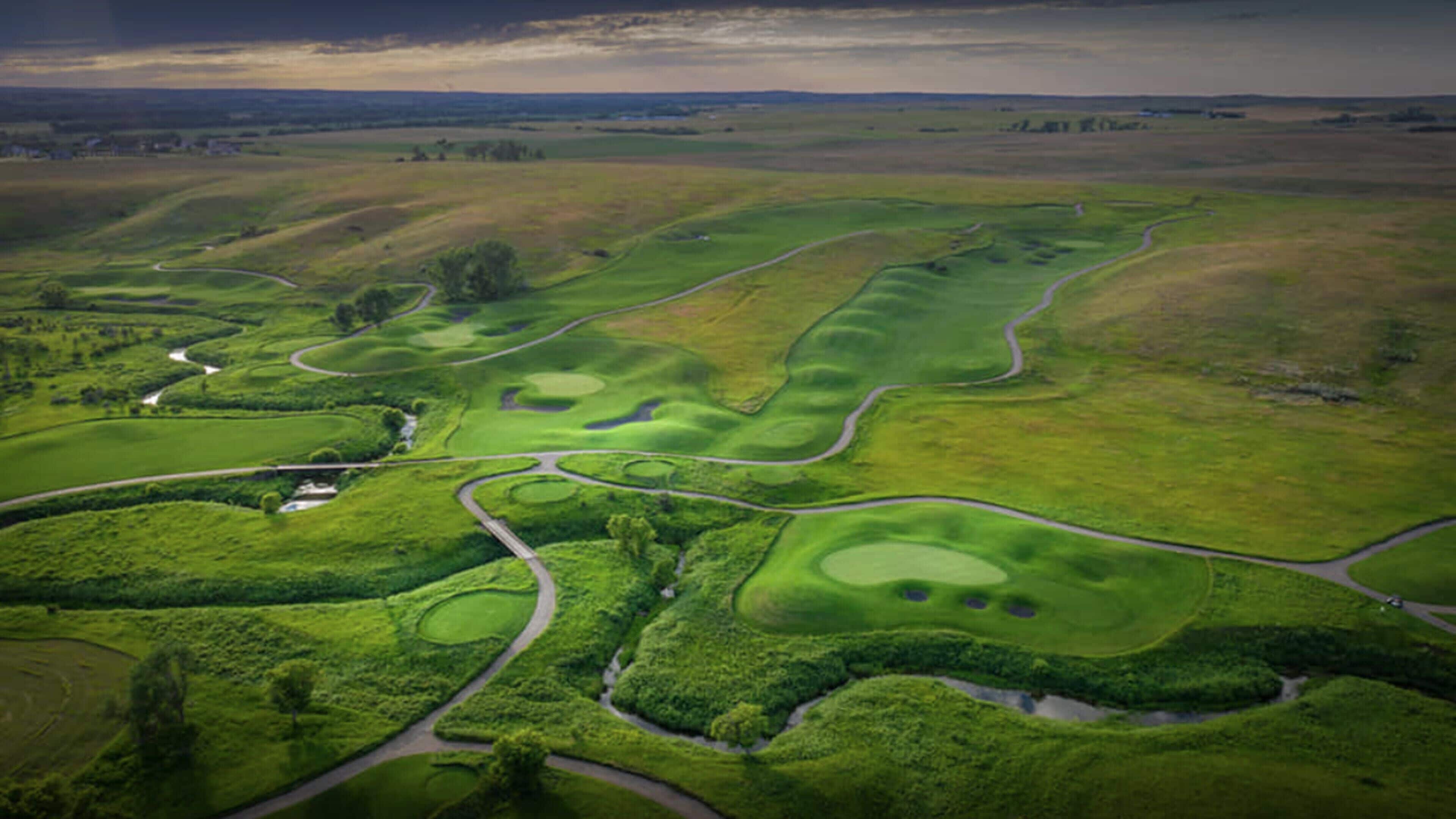 Vue aérienne d’un parcours de golf comportant plusieurs allées, des greens et des obstacles d’eau.