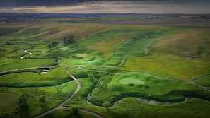 An aerial view of a golf course with multiple fairways, greens, and water hazards. - Holiday Inn Bismarck by IHG (Bismarck)