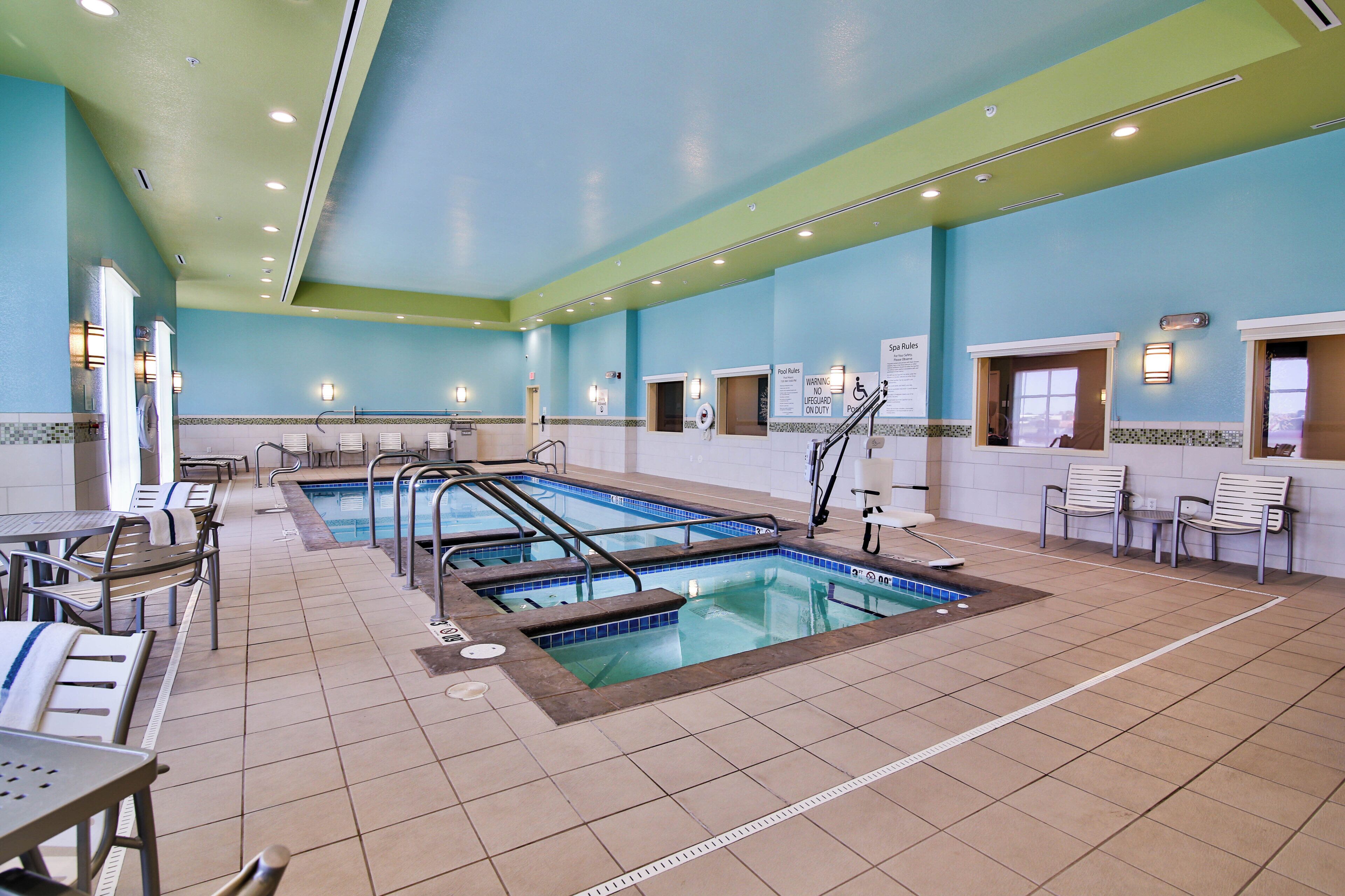 Un espace piscine doté de plusieurs couloirs de nage, de rampes de sécurité et de chaises longues.
