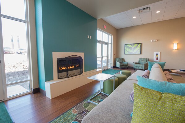 A modern lounge area with a fireplace, comfortable seating, and large windows. - Holiday Inn Bismarck by IHG (Bismarck)