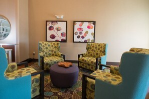 A room with four patterned armchairs, a round ottoman, and two framed artworks on the wall. - Holiday Inn Bismarck by IHG (Bismarck)