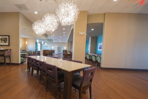 A spacious dining area with a long table and multiple chairs, overhead lighting, and a visible exit sign. - Holiday Inn Bismarck by IHG (Bismarck)