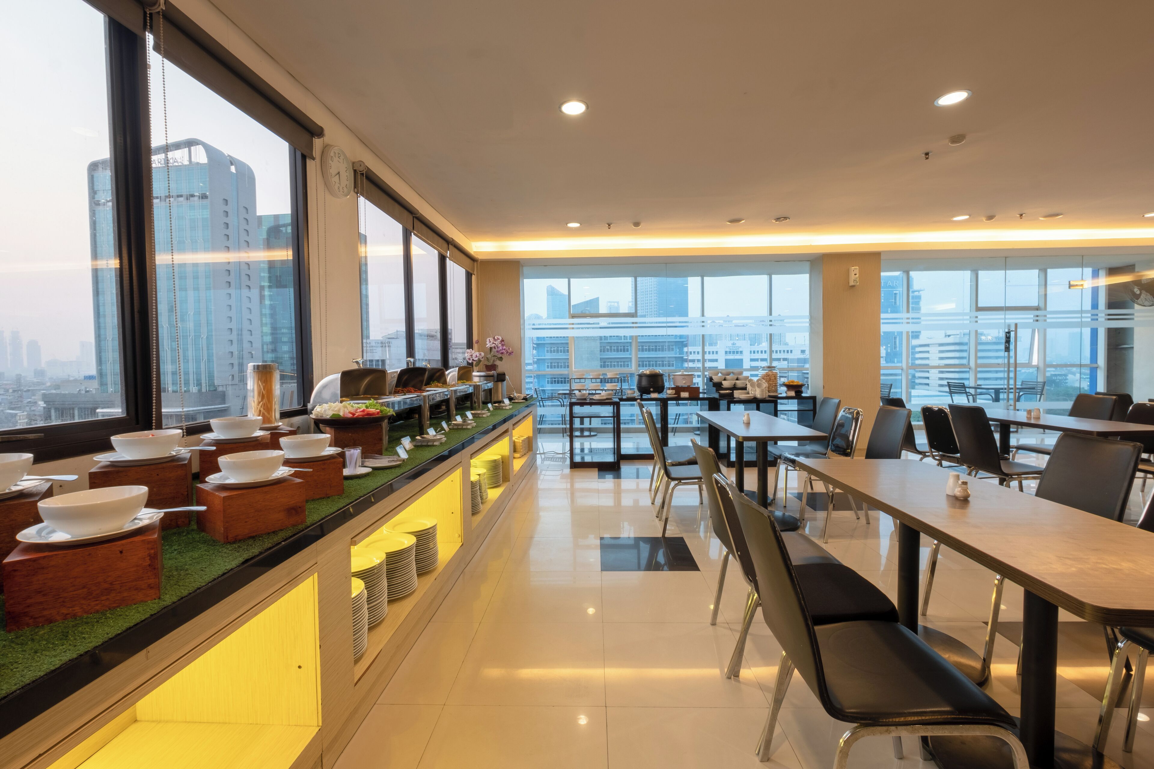 A modern dining area with a buffet setup, large windows, and a view of the cityscape.