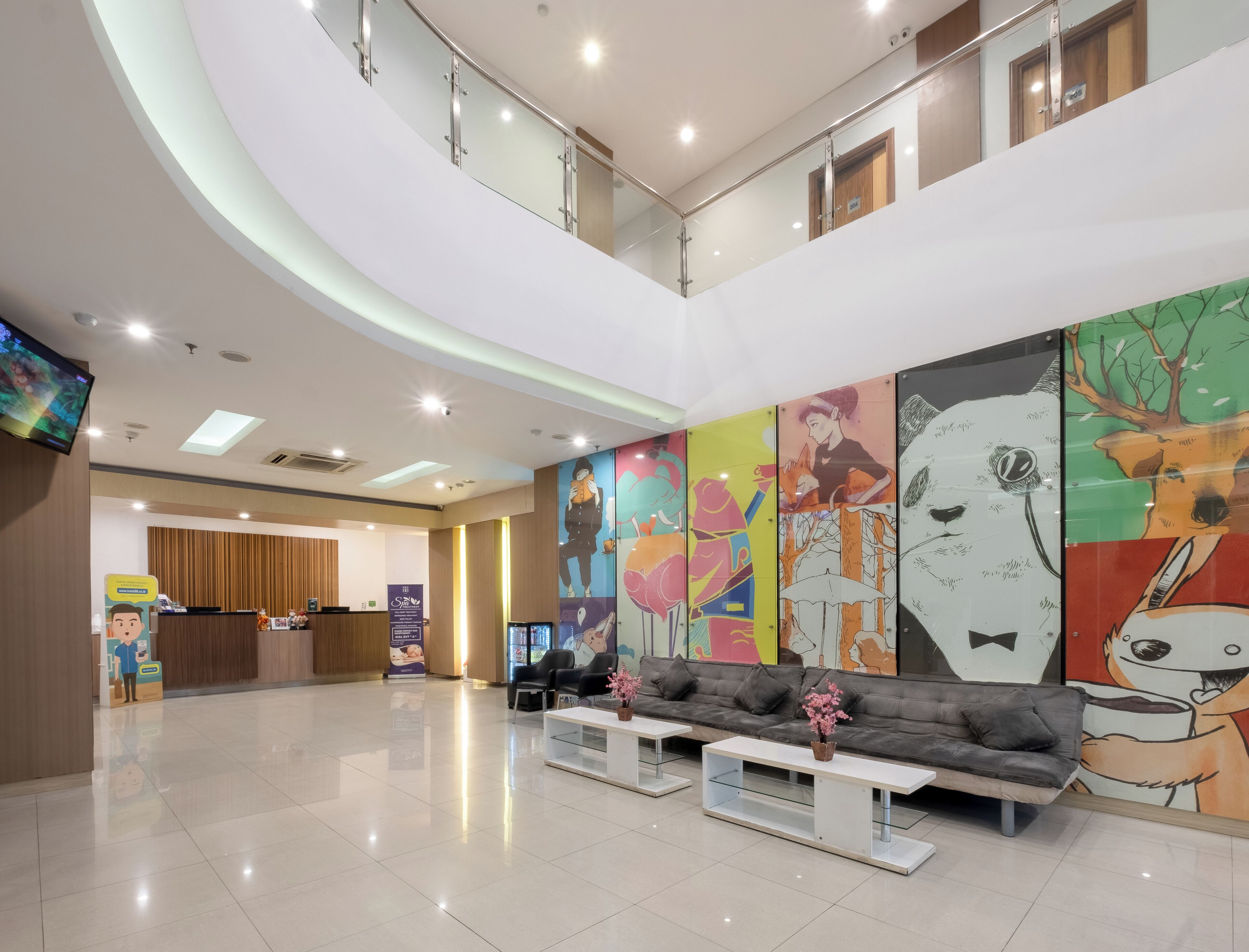 A modern hotel lobby with a reception desk, seating area, and a large mural on the wall.