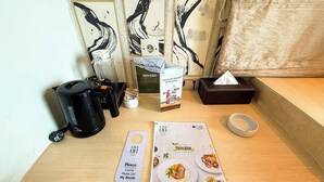 A hotel room with a wooden table, a coffee maker, a menu book, a tissue box, and a sign indicating the room number. - Hotel 88 Grogol by WH (Jakarta)