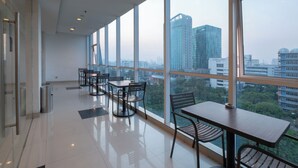 A modern dining area with large windows, a clean floor, and a view of the cityscape. - Hotel 88 Grogol by WH (Jakarta)