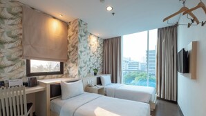 A hotel room with two beds, a desk, a chair, a TV, and a window with a city view. - Hotel 88 Grogol by WH (Jakarta)