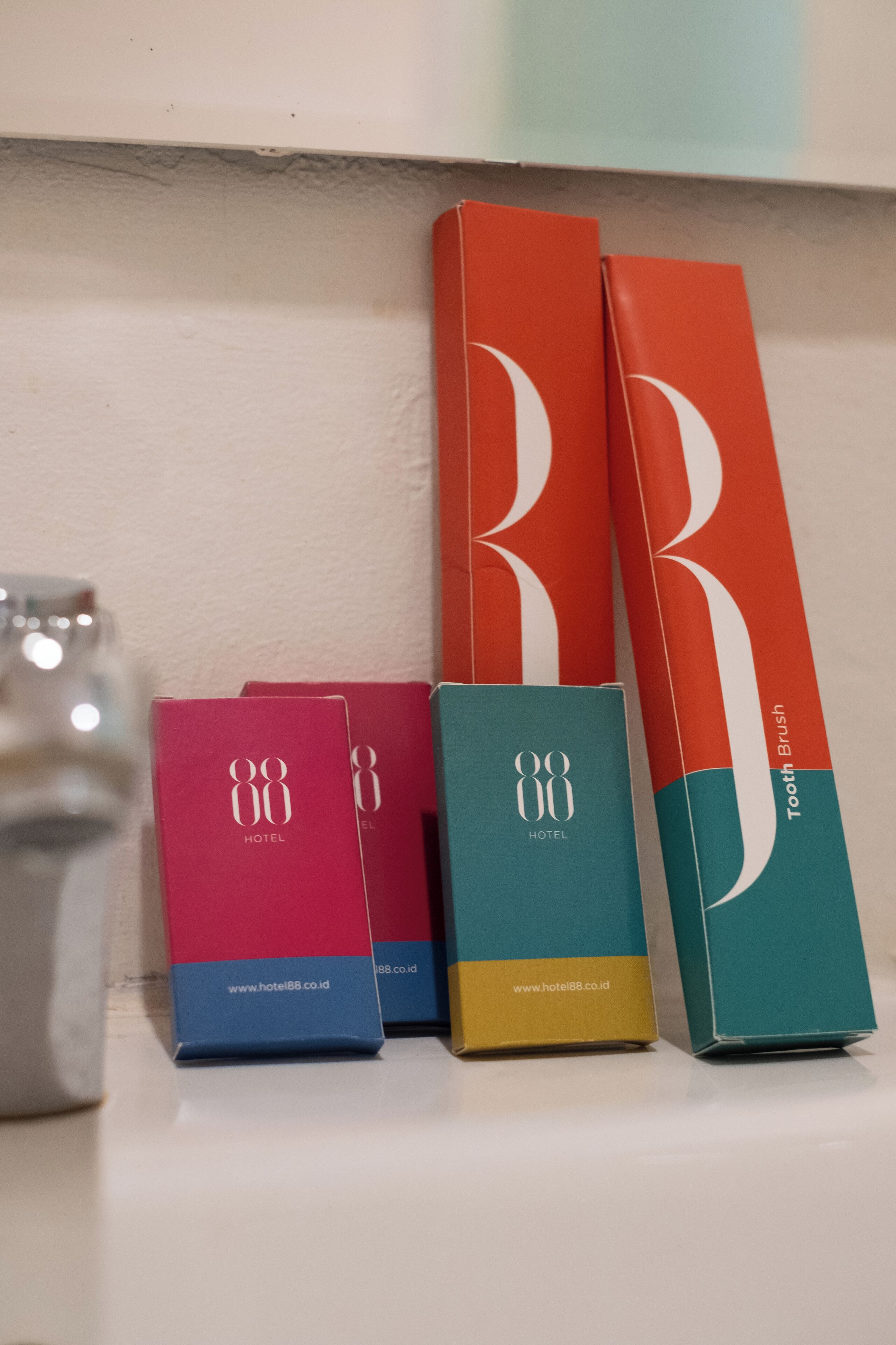 Four boxes of Hotel88 products, including a toothbrush and a tube of toothpaste, arranged on a shelf.