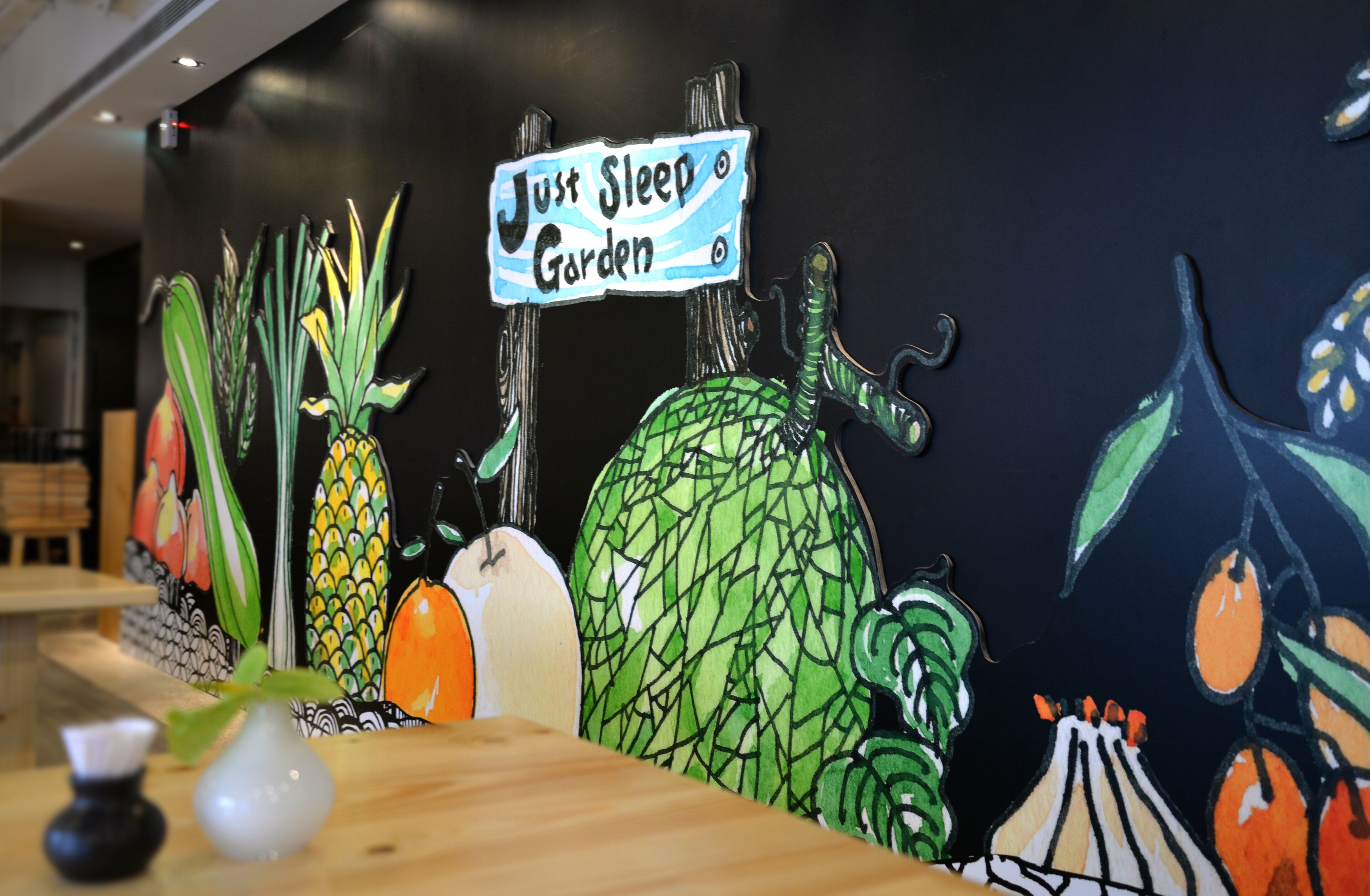 Eine Wand mit einem Schild, das "Just Sleep Garden" zeigt, und verschiedenen Fruchtabbildungen.
