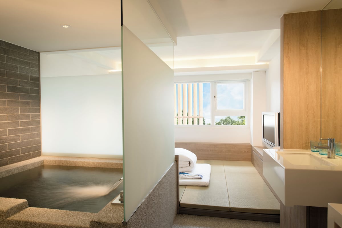 A modern bathroom with a bathtub, a sink, and a window.