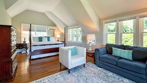 A bedroom with a large bed, a white armchair, a dark sofa, and a patterned rug. - 3 Waves Bed & Breakfast (Plymouth)