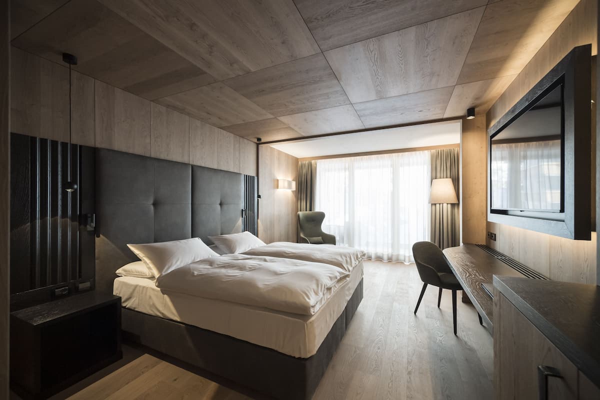 A modern hotel room with a large bed, a desk, and a TV.