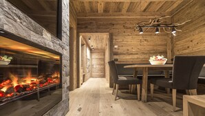 A wooden interior with a fireplace, dining table, and chairs. - Hotel Cappella (Corvara in Badia)