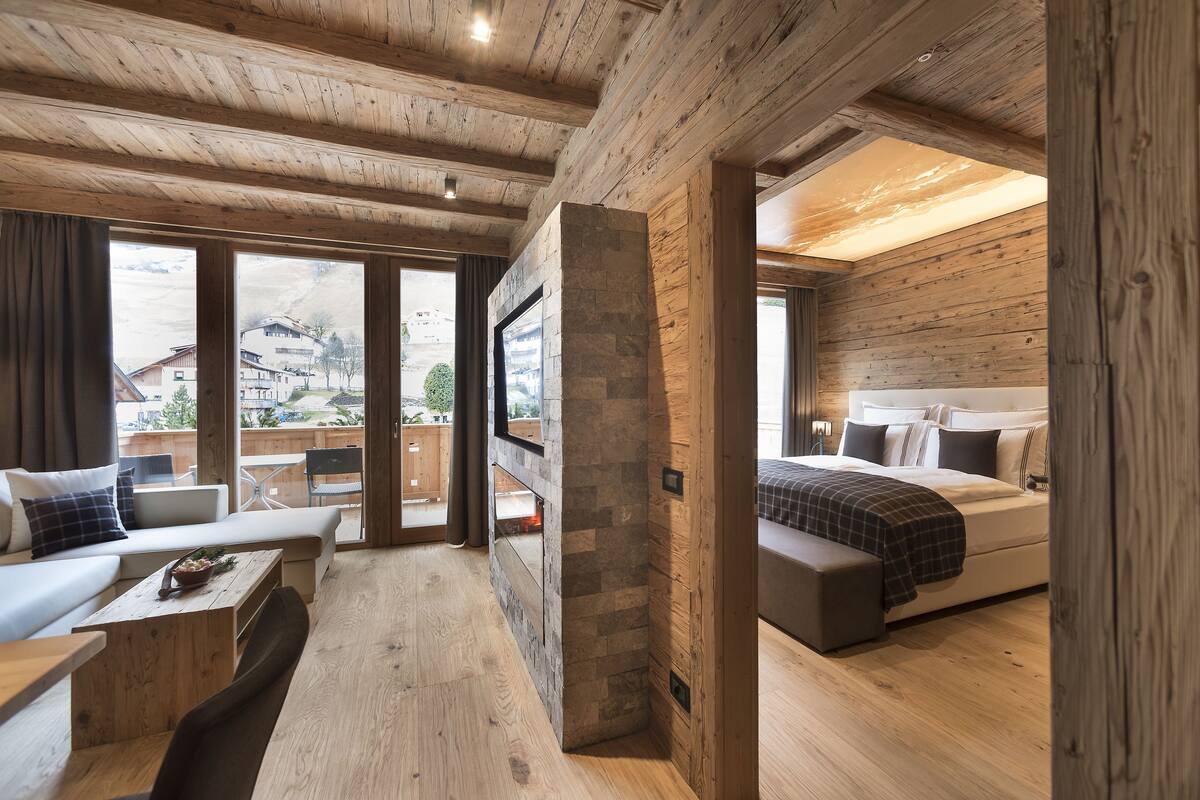 A modern log cabin interior with a large bed, a sofa, and a dining area.