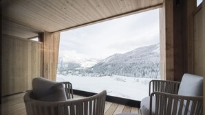 A wooden interior with a large window overlooking a snowy landscape. - Hotel Cappella (Corvara in Badia)