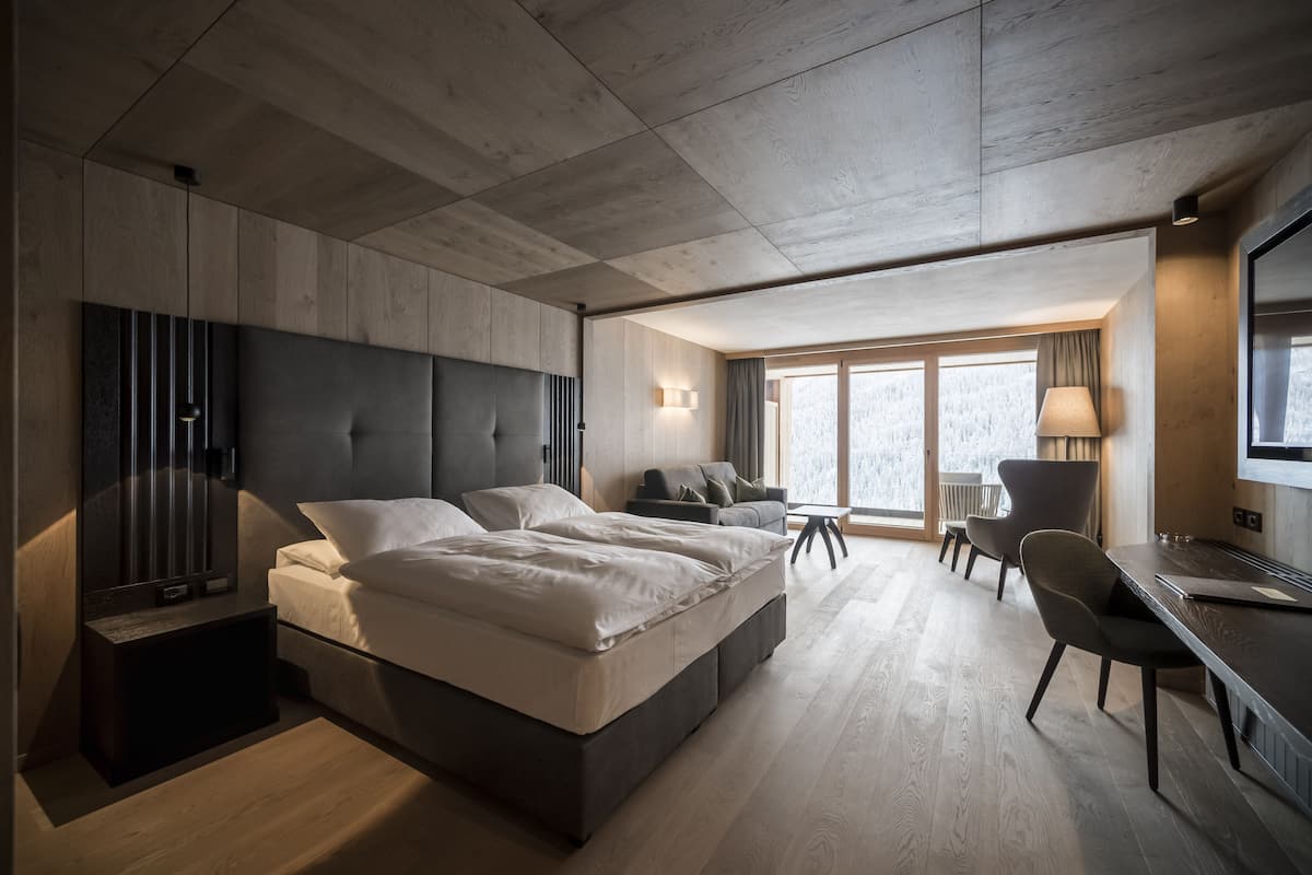 A modern bedroom with a large bed, a desk, and a chair.