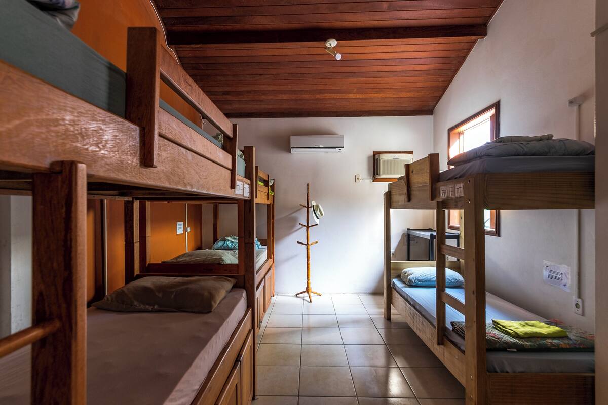 Ein Schlafsaalzimmer mit Etagenbetten, einer Holzzieldecke und einem Fliesenboden.