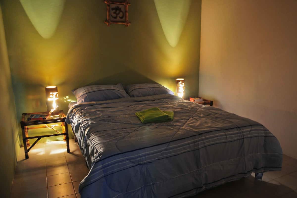 Ein Schlafzimmer mit einem Bett, zwei Nachttischen und einem Wandbild.