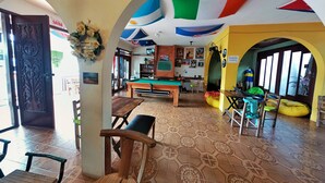 Una habitación con mesa de billar, sillas, sofá y una exhibición de banderas.