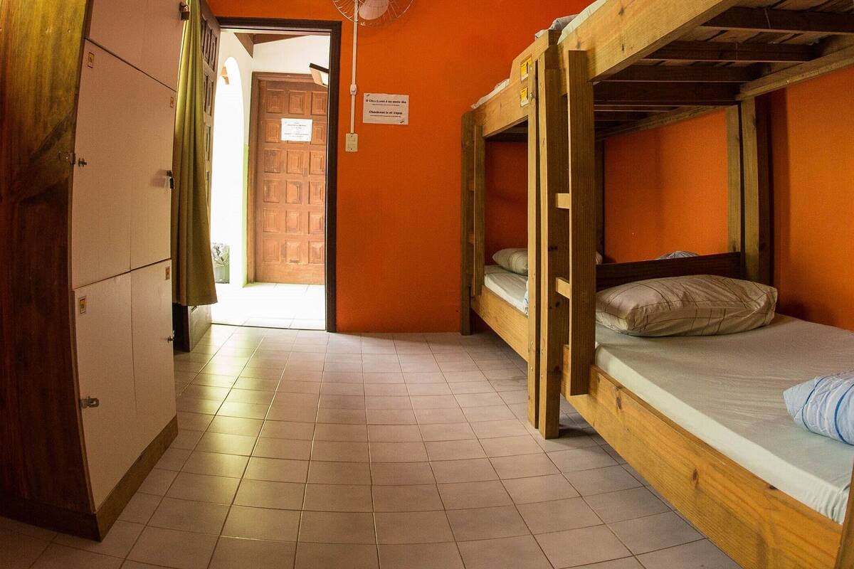 Ein schmaler Gang mit Etagenbetten und einer Tür zu einem weiteren Raum.