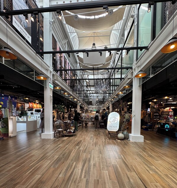 An indoor shopping mall with wooden flooring, multiple levels, and various stores.