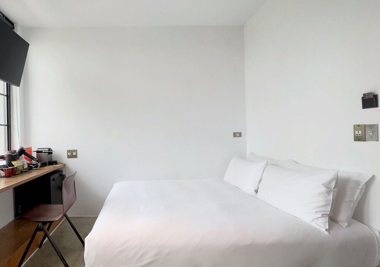 A bedroom with a bed, a desk, and a chair.