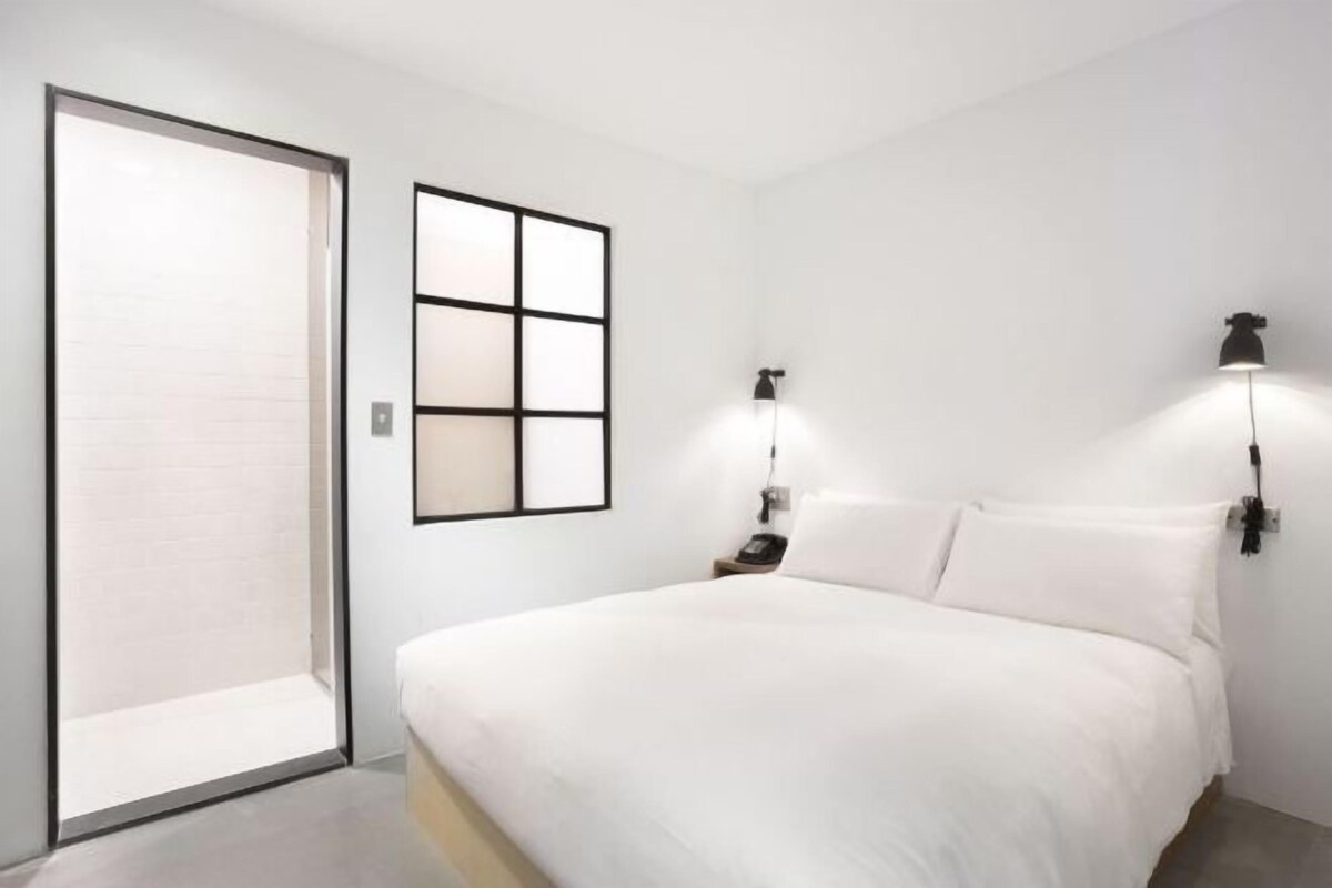 A bedroom with a bed, a sliding door, and two wall-mounted lamps.