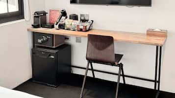 A modern hotel room with a large bed, a desk with a chair, a television, a mini-fridge, and a window with blinds.
