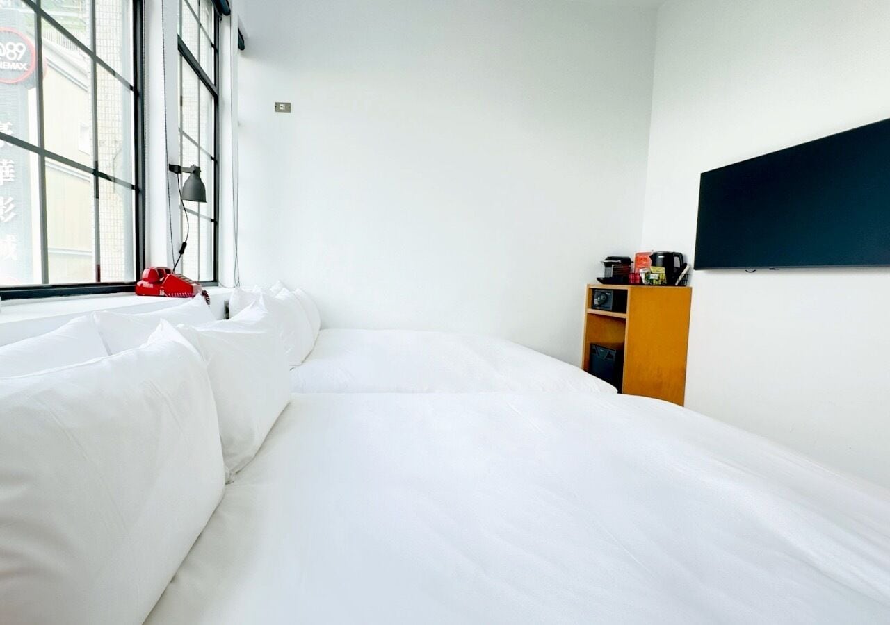 Quarto de hotel com uma cama grande, um sofá, uma TV e um pequeno armário de madeira.