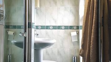 Un baño con mampara de vidrio, inodoro, lavabo y perchero para toallas.