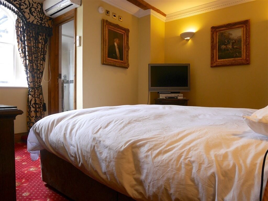 A hotel room with a large bed, a flat-screen TV, and two framed pictures on the wall.