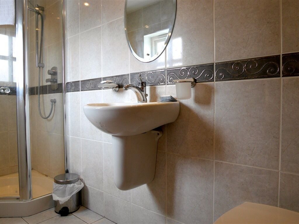 A bathroom with a sink, mirror, and shower.