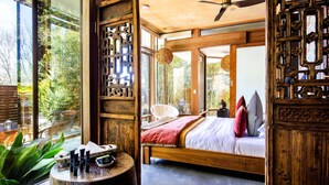 A spacious bedroom with a large bed, wooden furniture, and a view of greenery through large windows. - Sticky Rice Villas (Stirling)